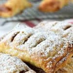 puff pastry apple turnovers on a white plate dusting with powdered sugar