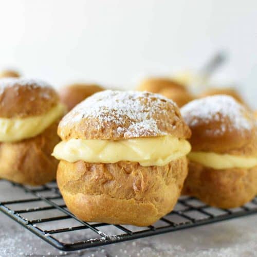 pastries filled with custard on black wire rack viewed from front on
