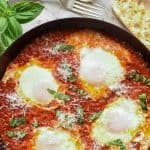 Text above image " Italian Eggs in Purgatory easy pantry meal"; image is four poached eggs in tomato sauce in black pan viewed from above