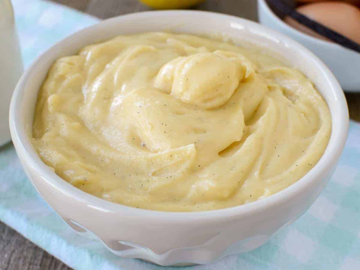 white bowl of pastry cream on pale blue cloth.