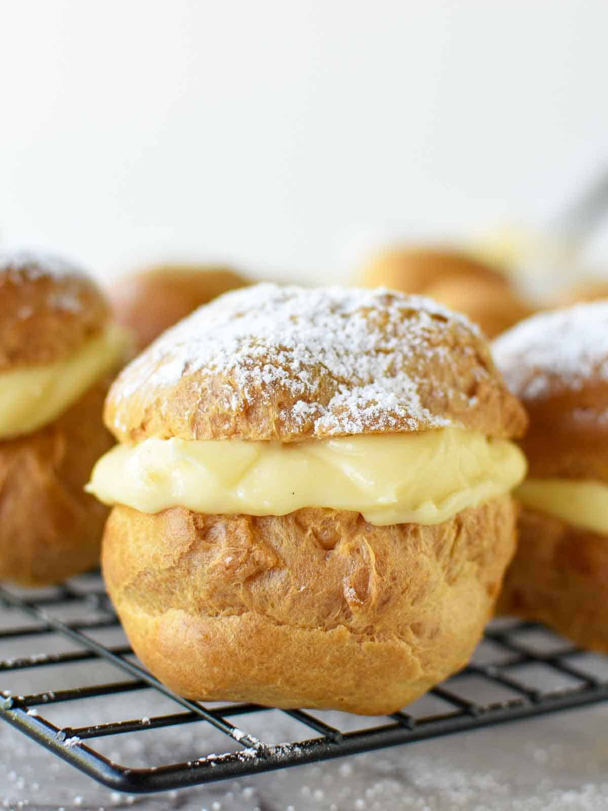 pastries filled with custard on black wire rack viewed from front on