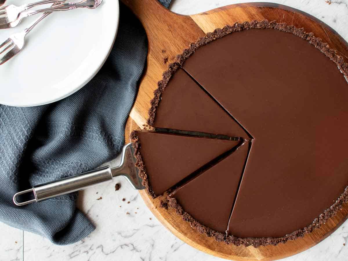 whole chocolate tart with 3 slices cut.