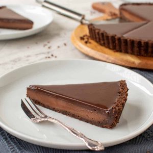 slice of chocolate tart with whole tart in the background