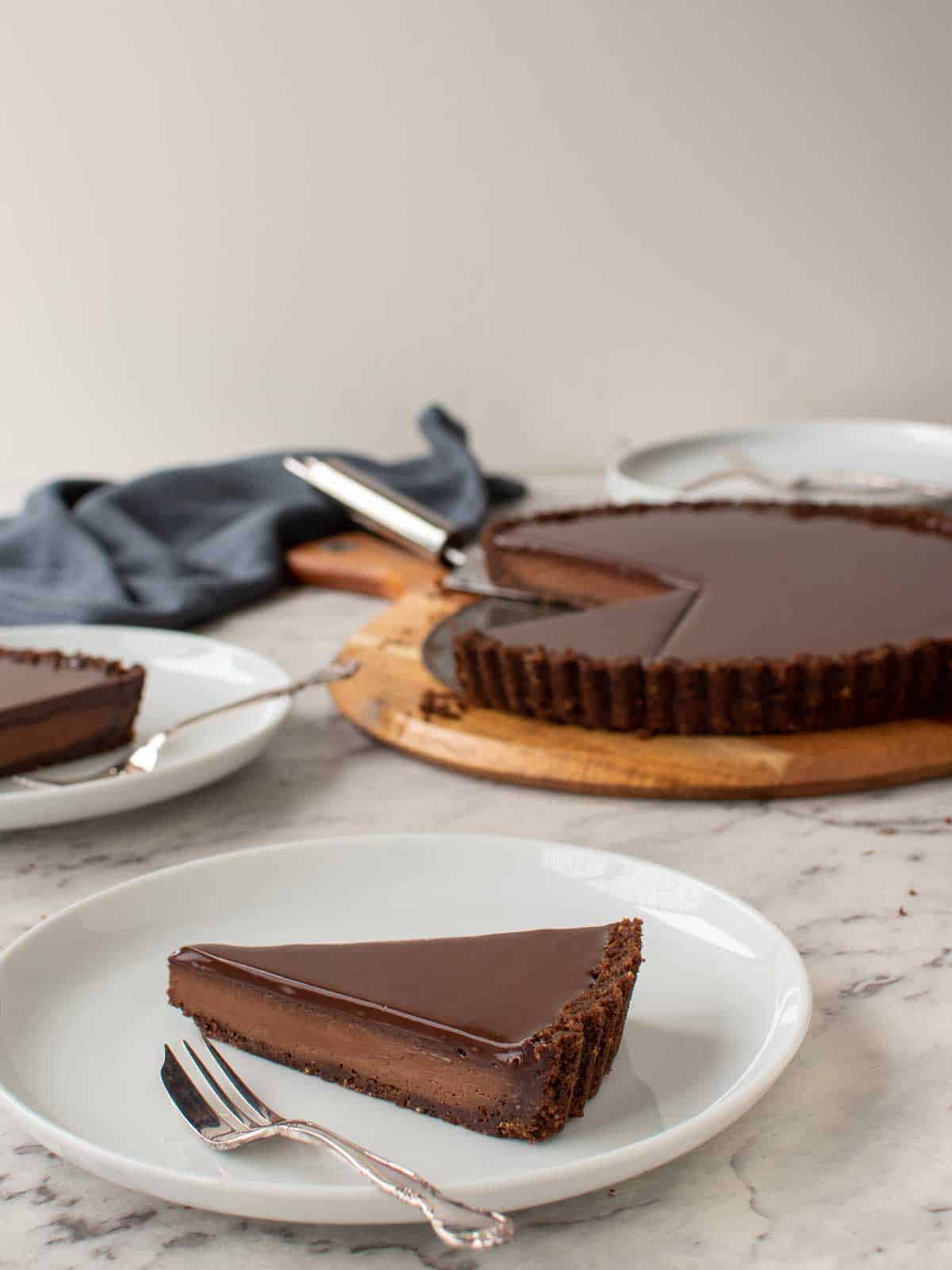 slice of chocolate tart with whole tart in the background.