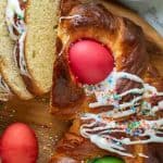 image and text; text reads "Italian easter bread"; image is close up of baked sweet bread decorated with red and green eggs and drizzle of icing and a few slice cut to show inside of bread