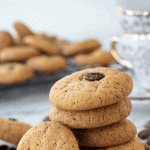 five cookies stacked with a sixth cookies leaning on the stack - cookies in the background and coffee beans scattered around