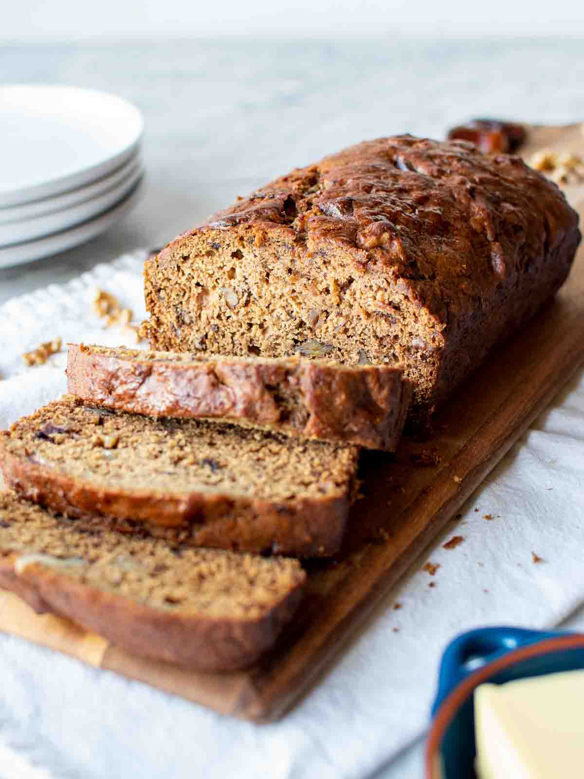 Date bread on wooden board with three slices cut.