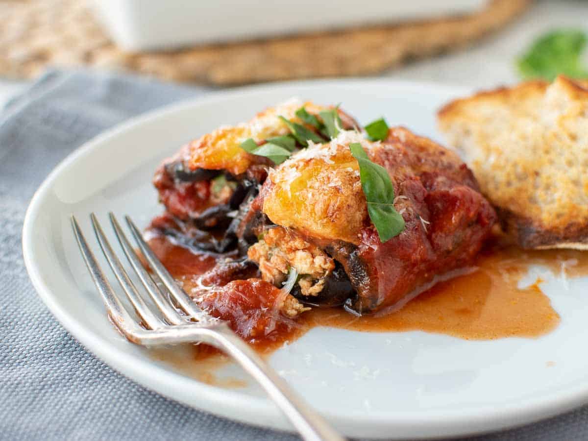 Eggplant, tomato sauce and cheese dish on a white plate.