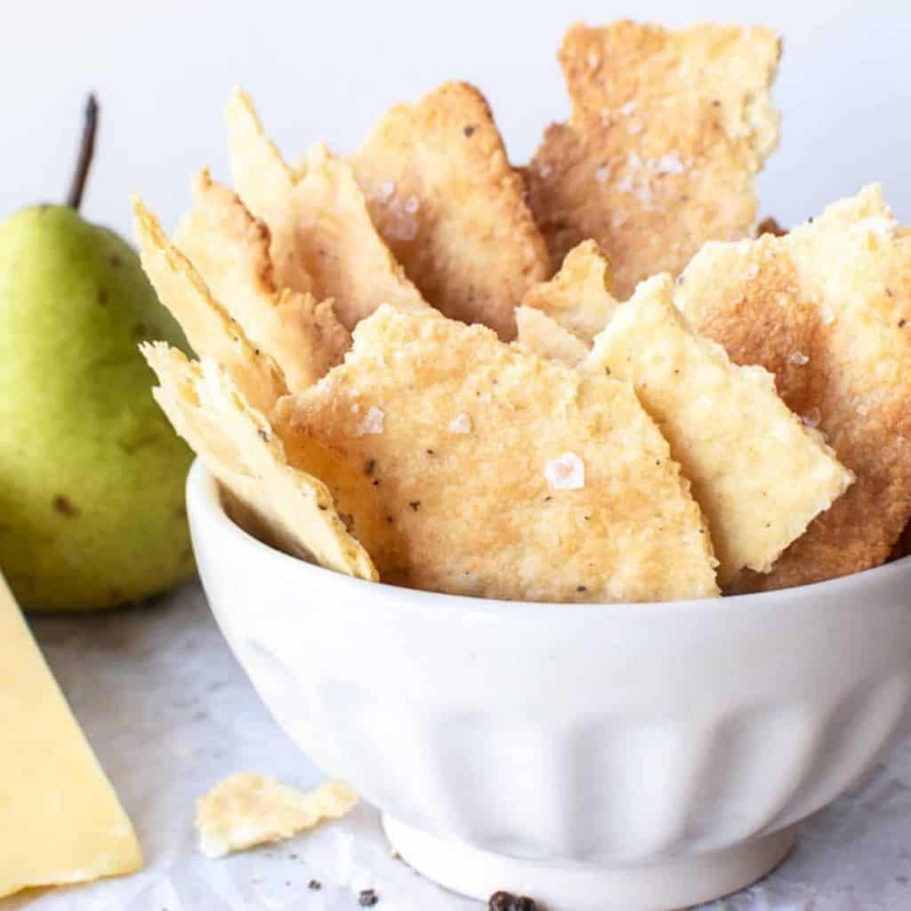 homemade crackers in white bowl with cheese and green pears