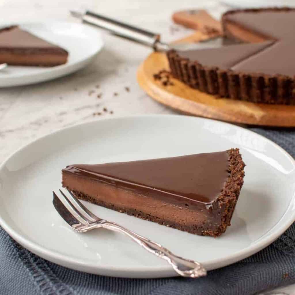 slice of chocolate tart with whole tart in the background
