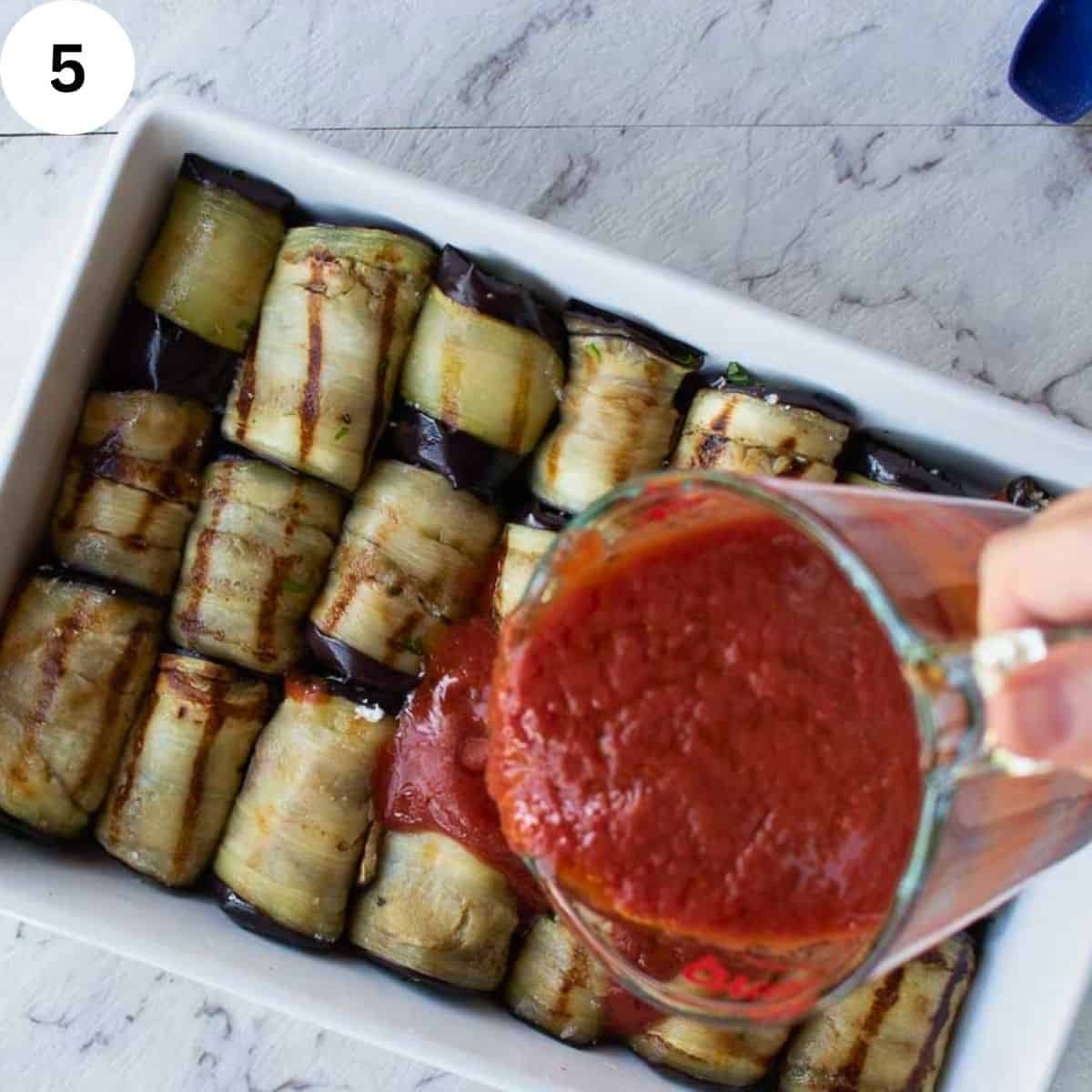 Pouring tomato puree over grilled and rolled eggplant slices.