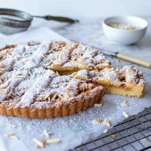 jam tart with lattice top sprinkled with powdered sugar with a slice cut