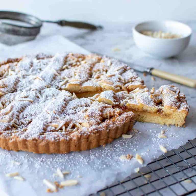 jam tart with lattice top sprinkled with powdered sugar with a slice cut