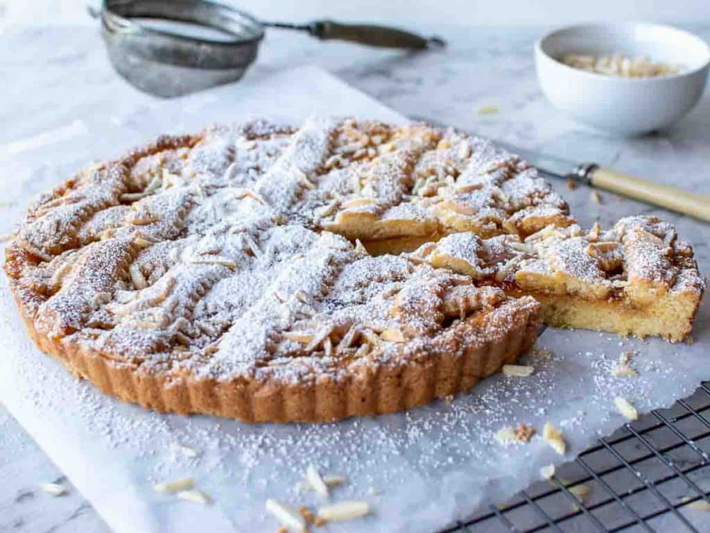jam tart with lattice top sprinkled with powdered sugar with a slice cut