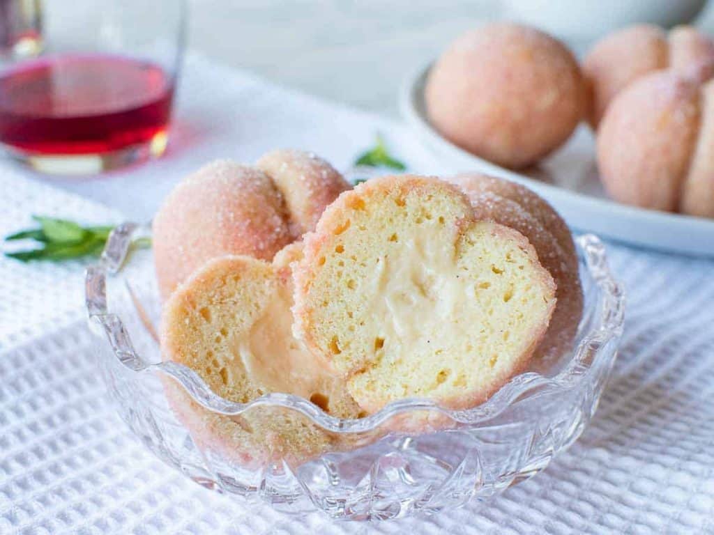 Italian Peach Cookies cut in half with cut side showing; more cookies in the background