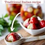 Image with text. Text reads Stuffed Cherry Peppers Traditional Italian Recipe. Image is one stuffed cherry pepper in a spoon and pile of stuffed cherry peppers in a white dish with bottles filled in the background