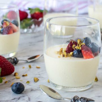 three vanilla panna cotta in glasses with strawberries and blueberries