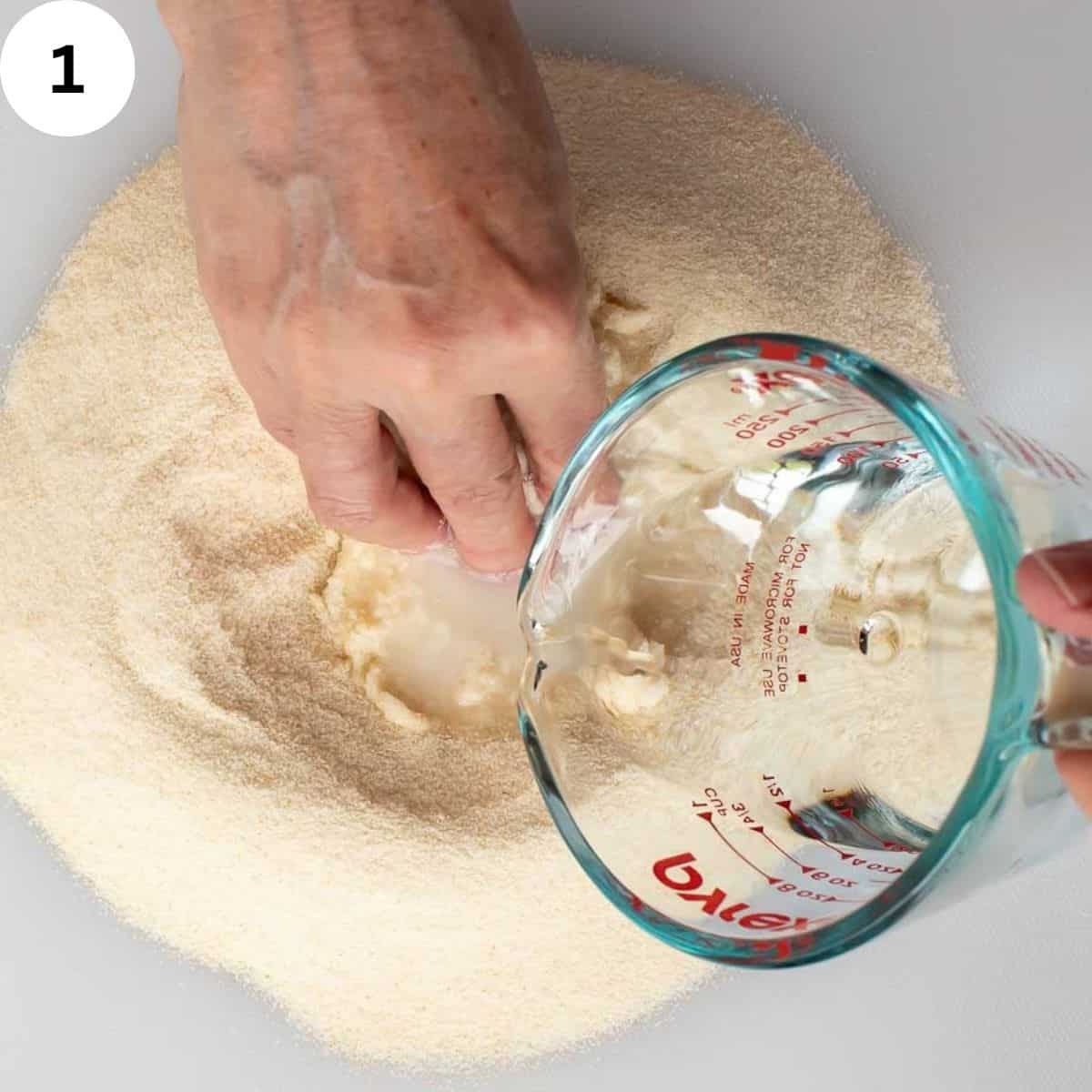 Mixing water into semolina with hands.