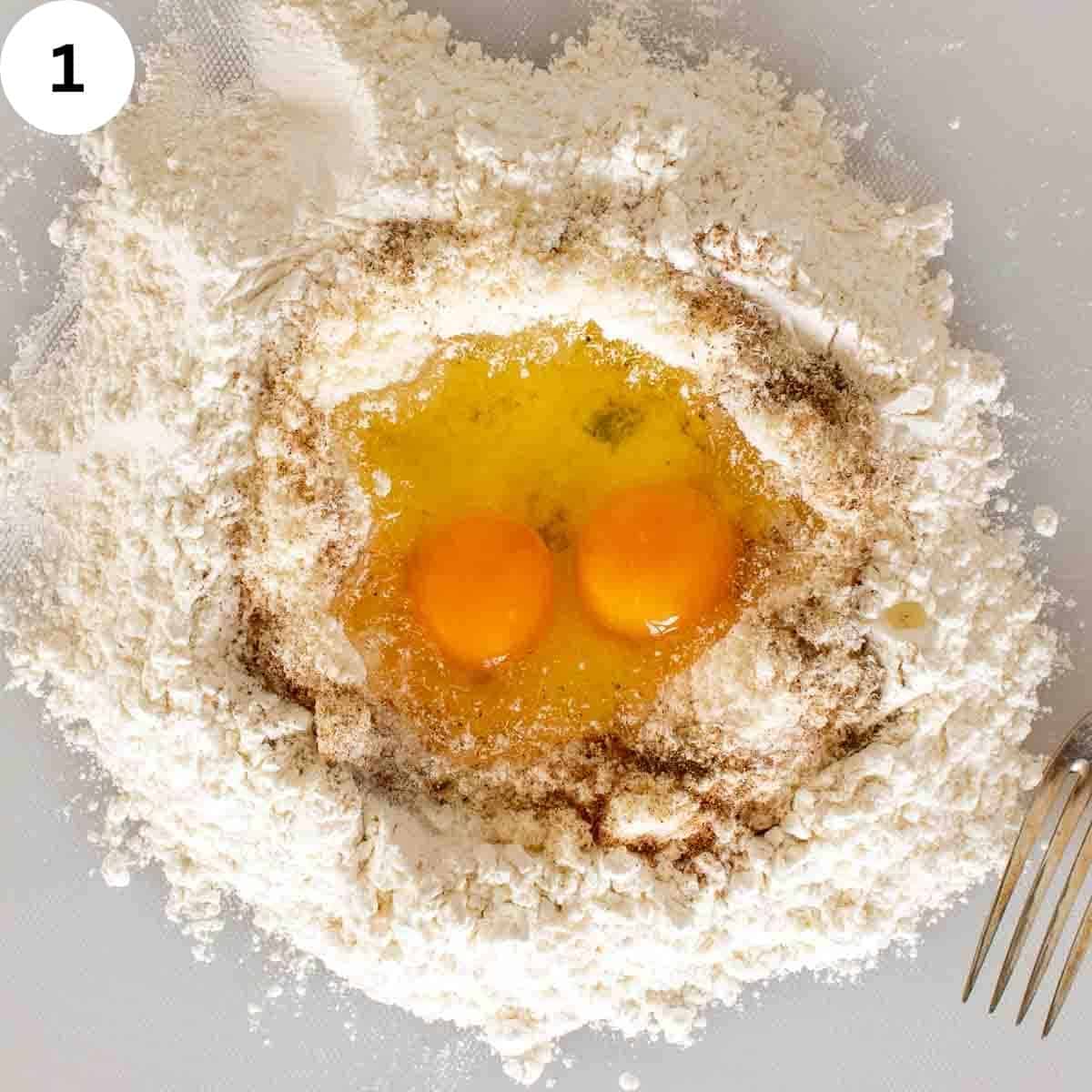 Flour with two eggs in the middle and spices sprinkled into the flour.