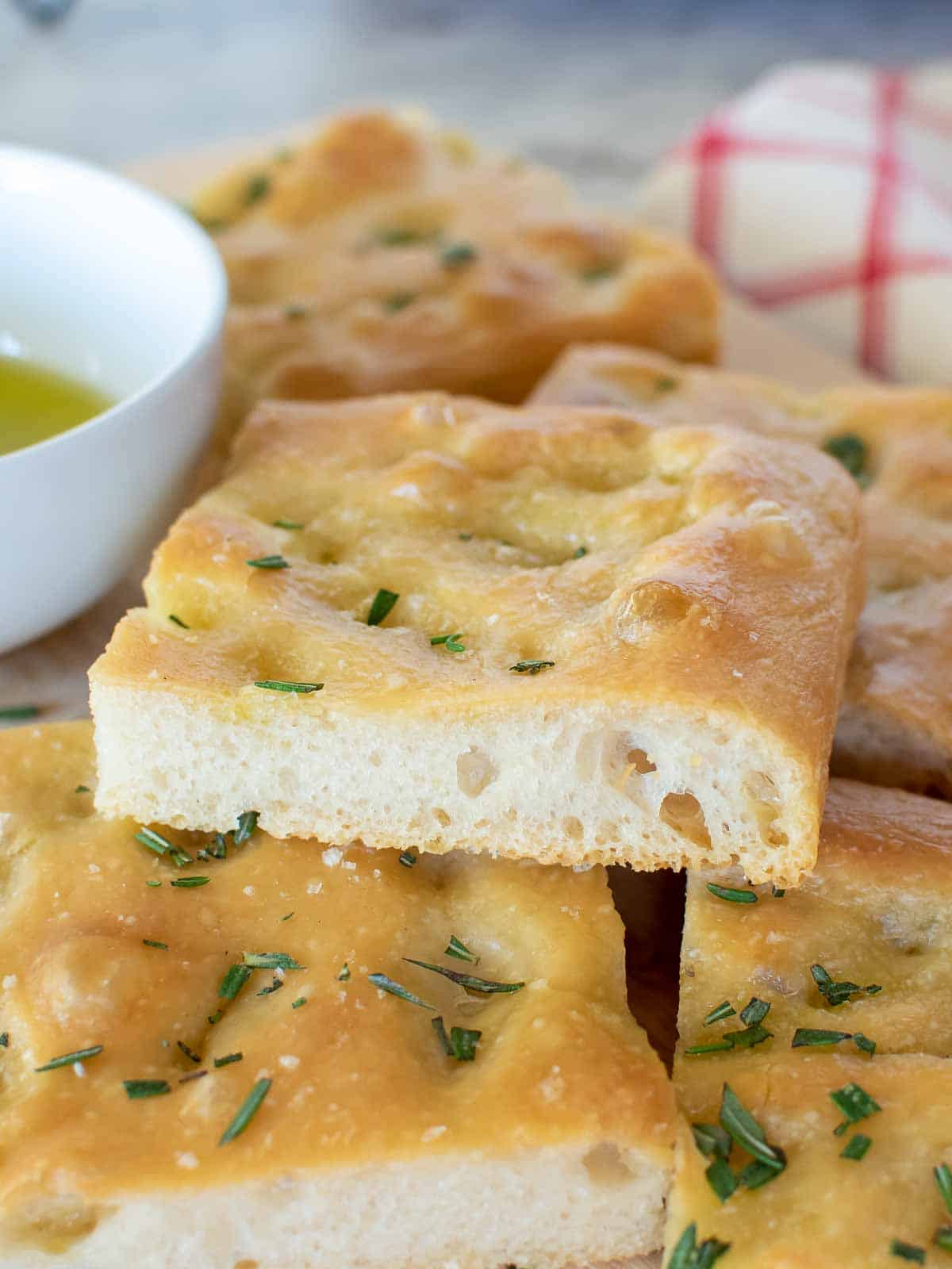 slices of focaccia stacked with white bowl of oil on the side.