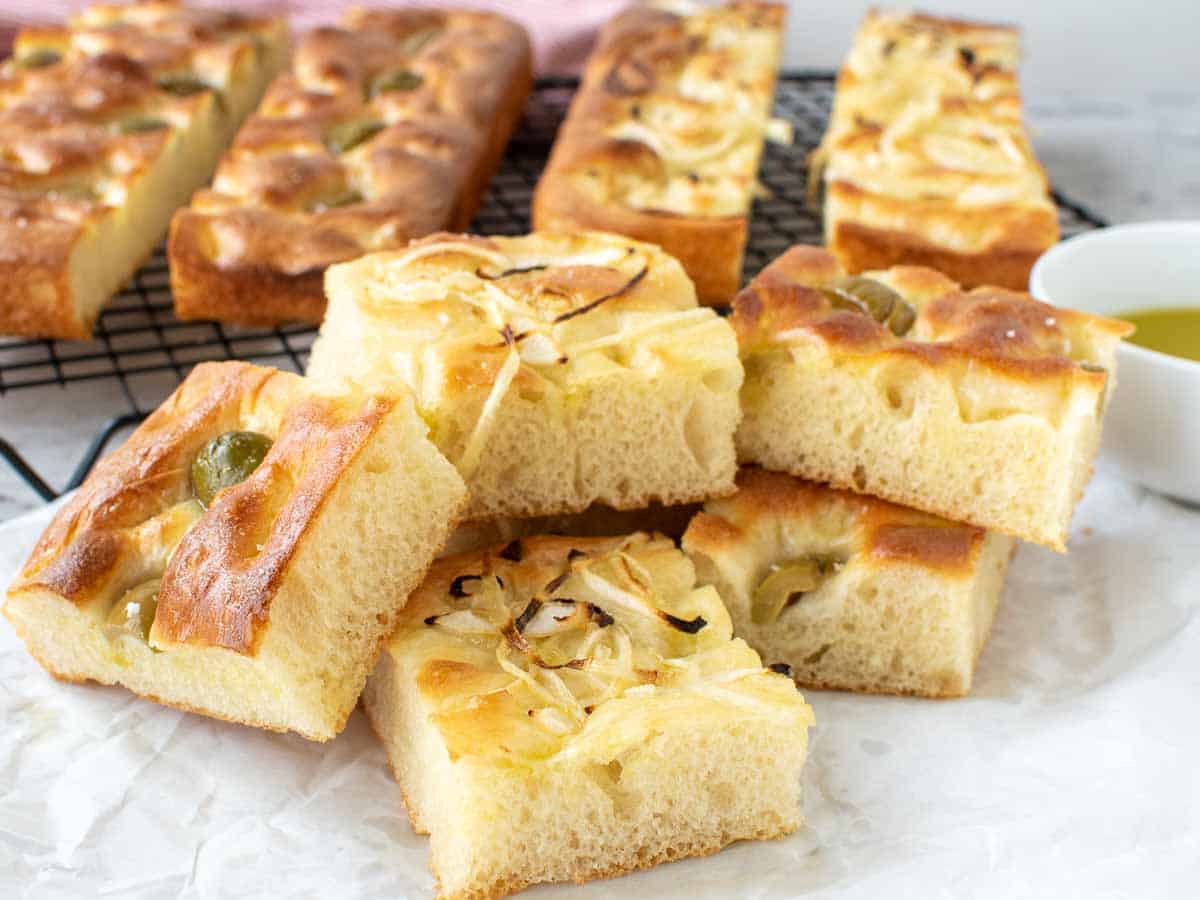 squares of bread topped with green olives and onions.