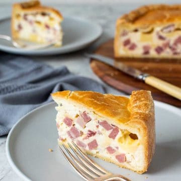 close up of a slice of italian pie with another slice and the whole pie in the background.