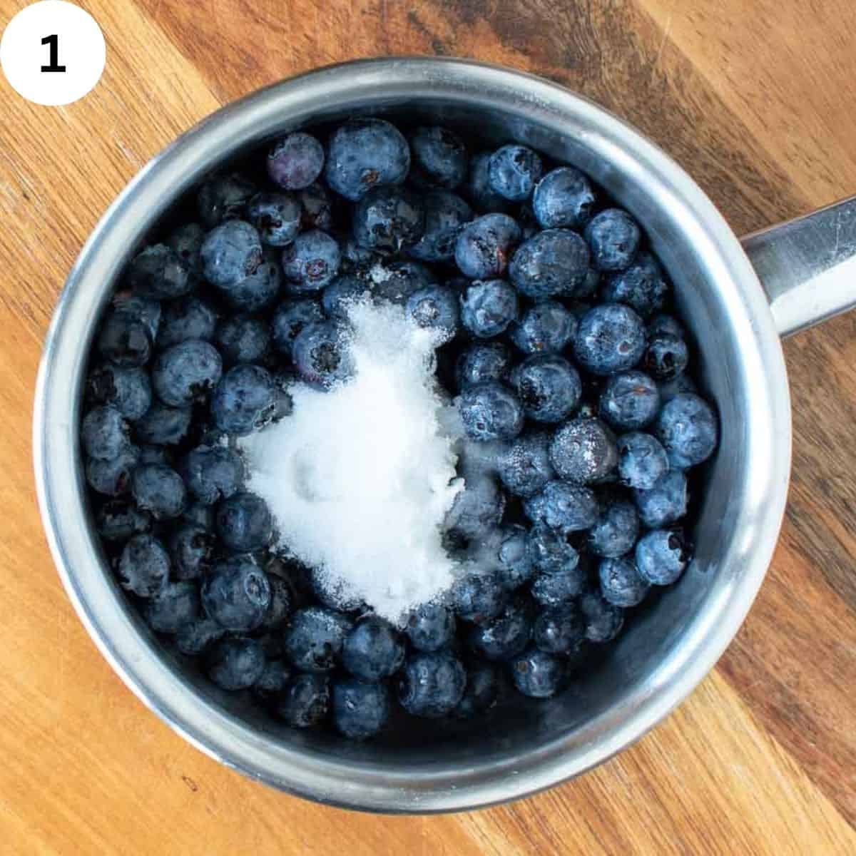 Blueberries and sugar in a saucepan.