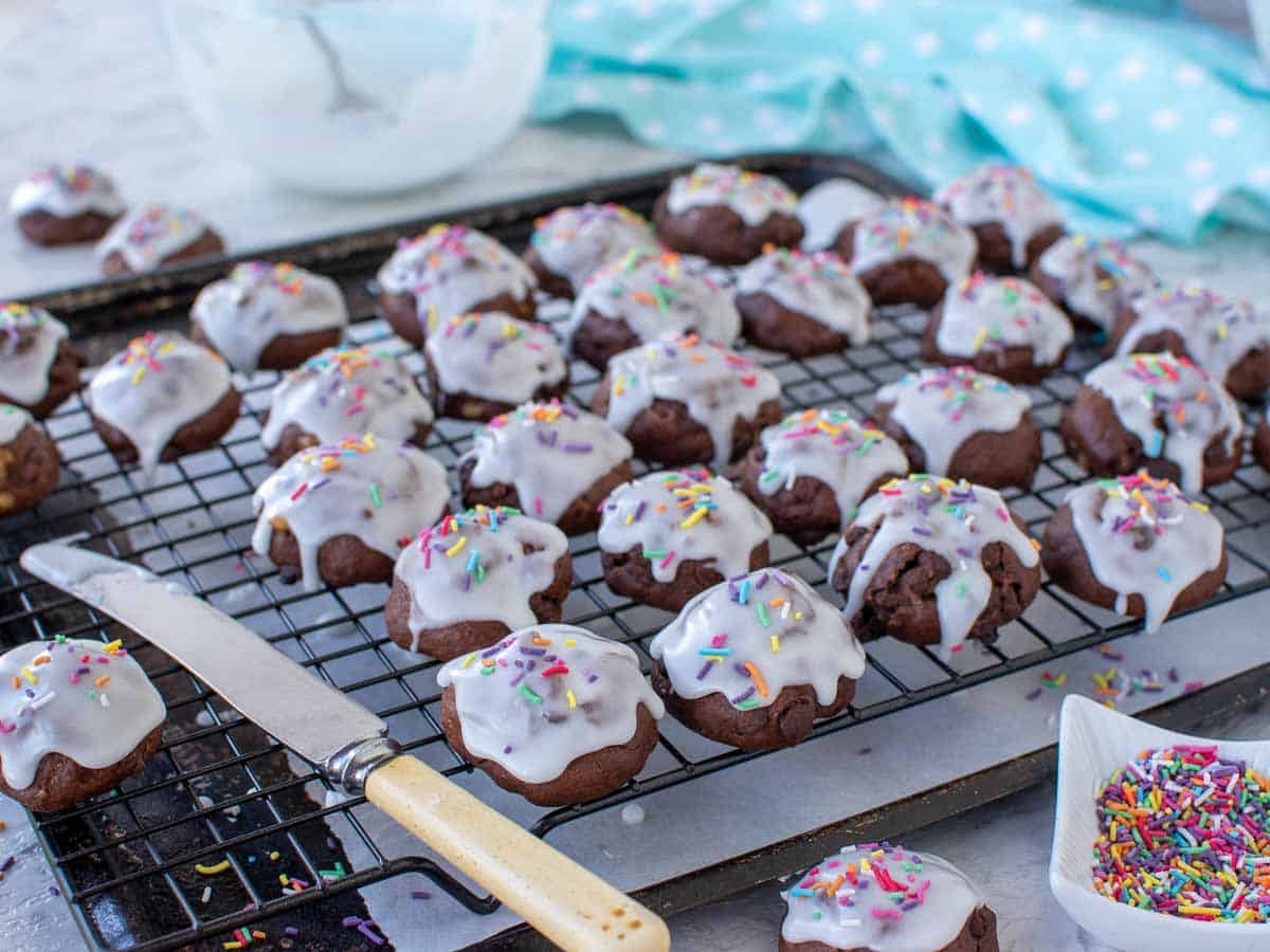 white frosting covered chocolate cookies on wire rack with retro knife.