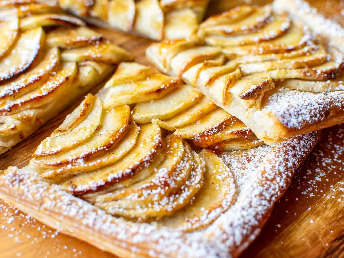 Close up slices of apple tart on wooden board.