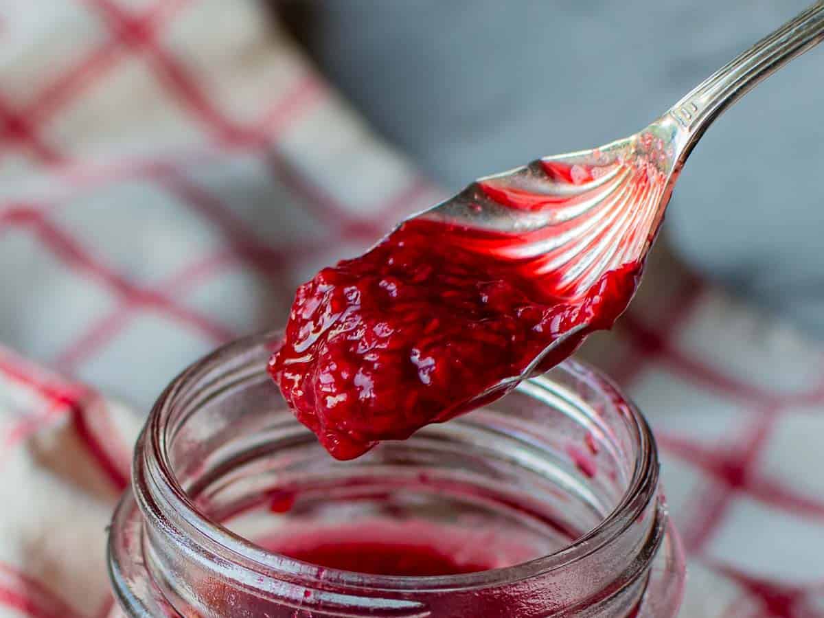 Close up of sauce made of raspberries on a spoon.