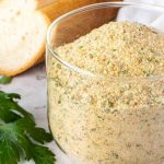 Italian bread crumbs in glass jar with a spoonful of crumbs.