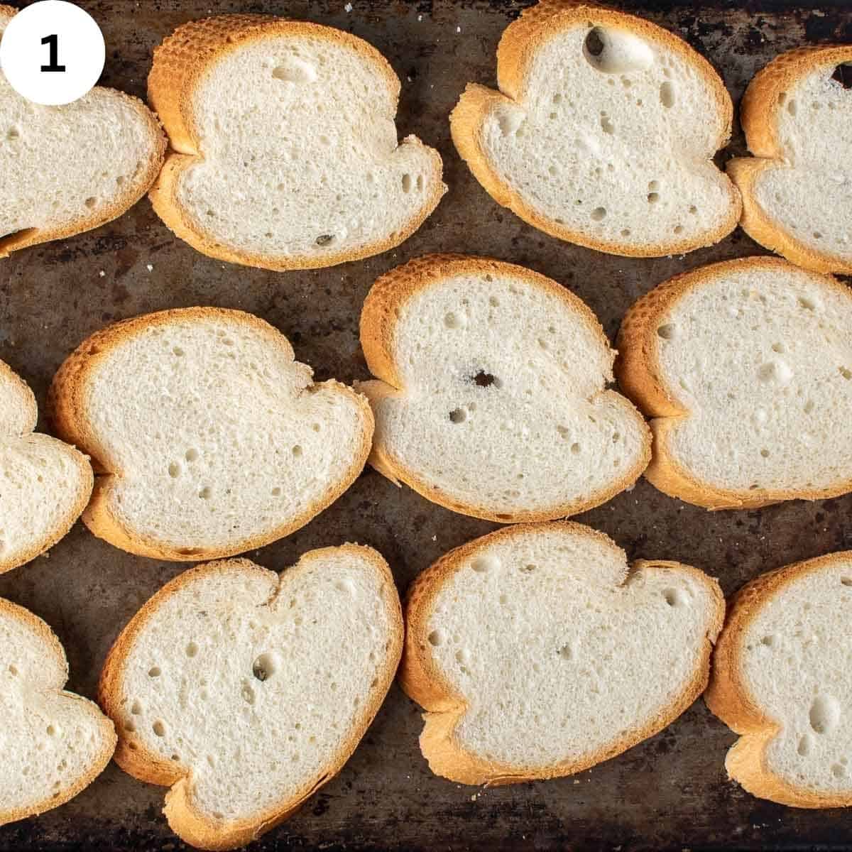 Slices of bread arranged on baking sheet.