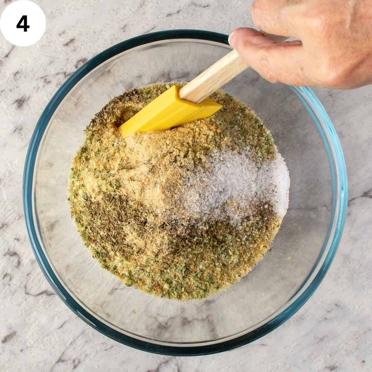 Bread crumbs, dried herbs and spices being stirred.