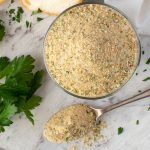 Italian bread crumbs in glass jar with a spoonful of crumbs viewed from above.