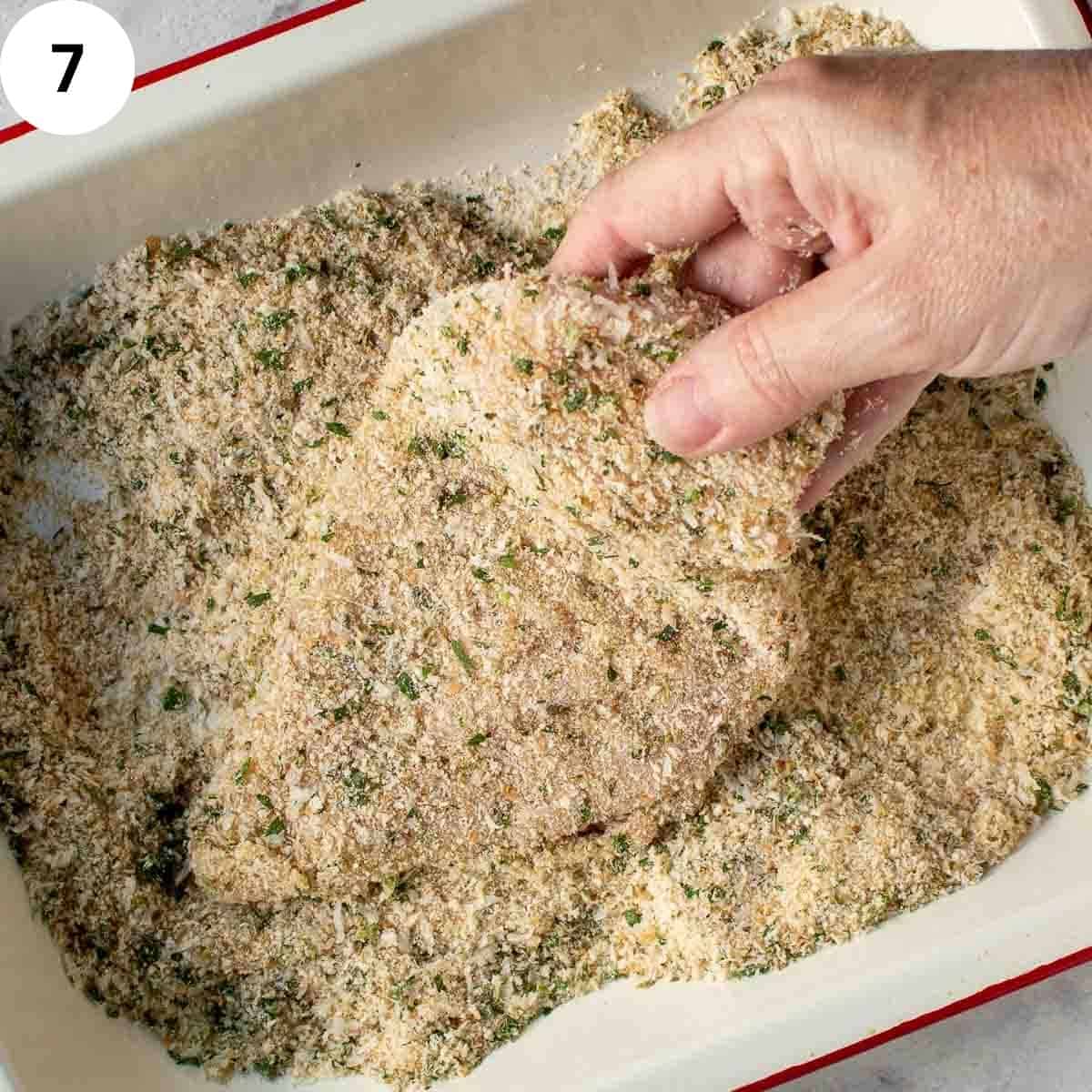 Uncooked chicken breast covered with breadcrumbs.