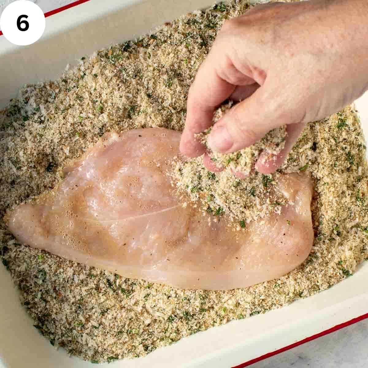 Covering chicken breast with breadcrumbs.