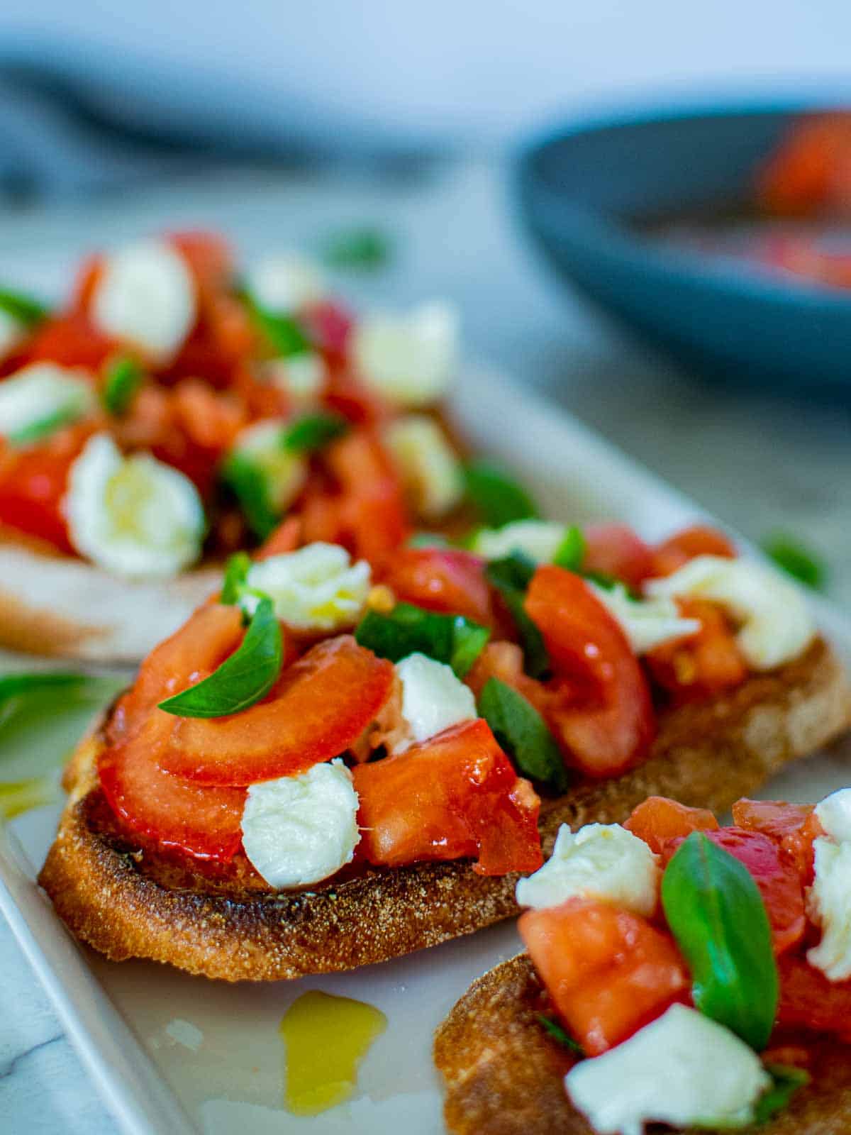 Bruschetta recipe with mozzarella and tomatoes on white plate.