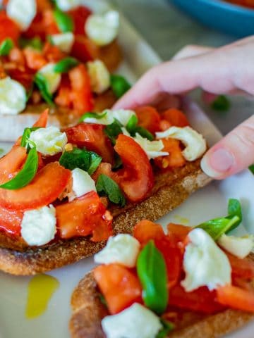 hand reaching for bruschetta with mozzarella.