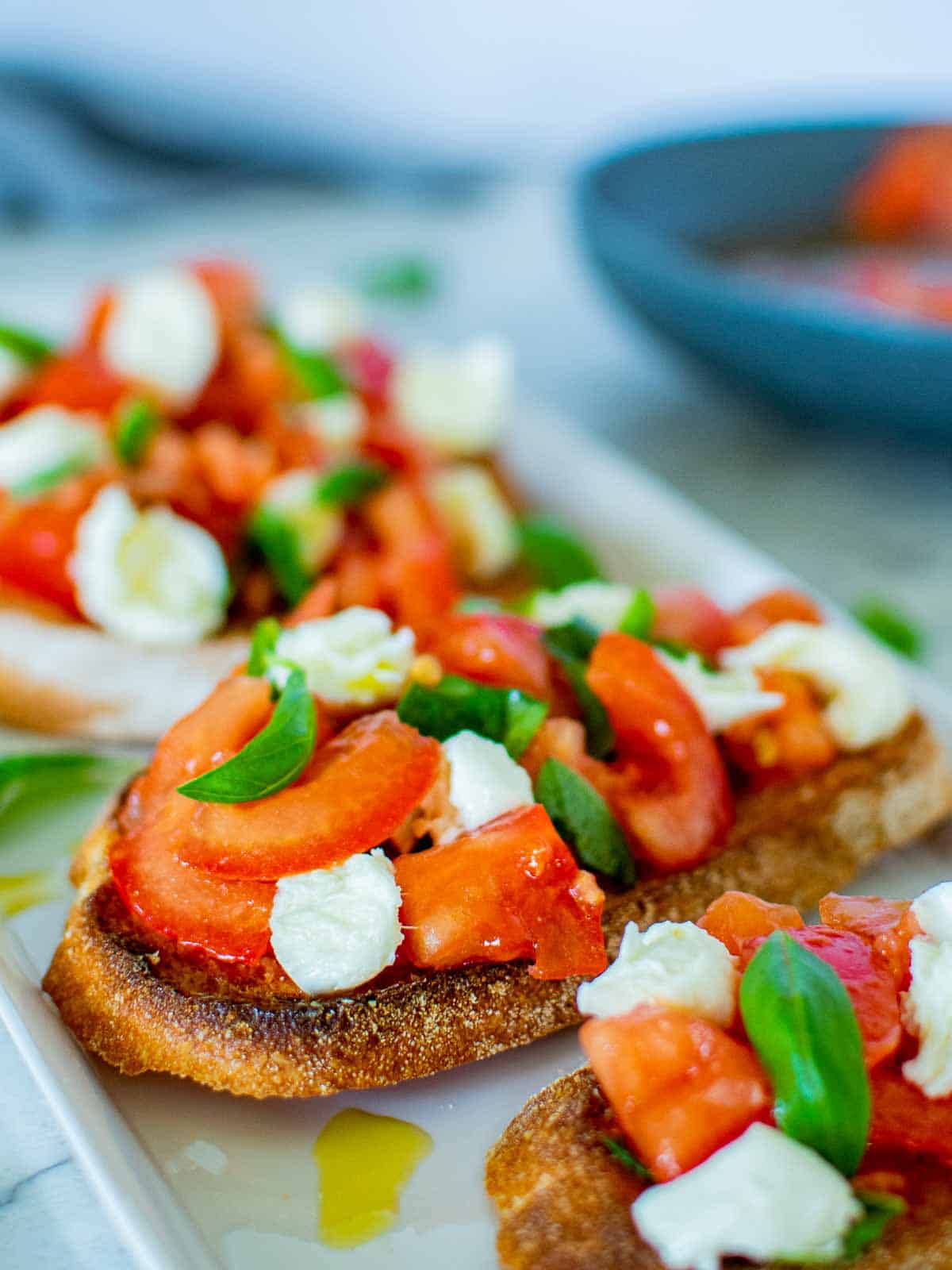 Bruschetta with mozzarella and tomatoes on a white plate.