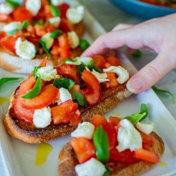 hand reaching for bruschetta with mozzarella.