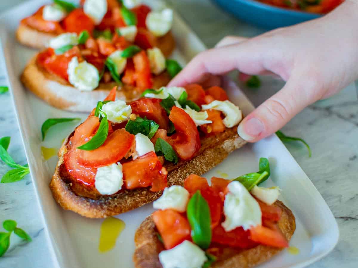 hand reaching for bruschetta