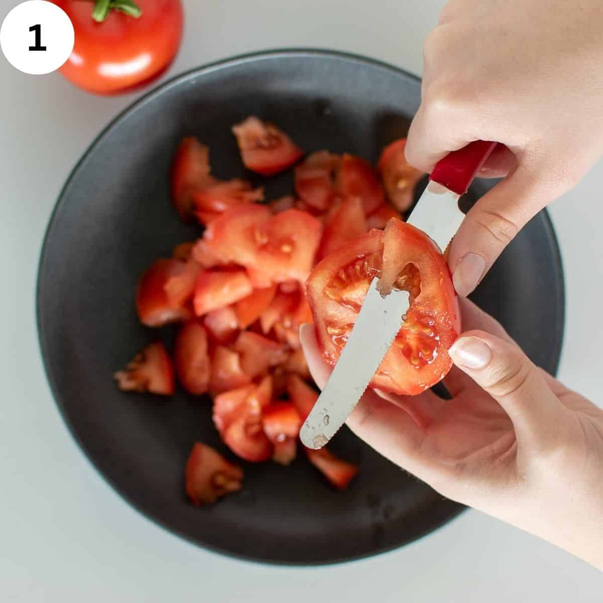 Cutting tomatoes with a knife above a bowl.