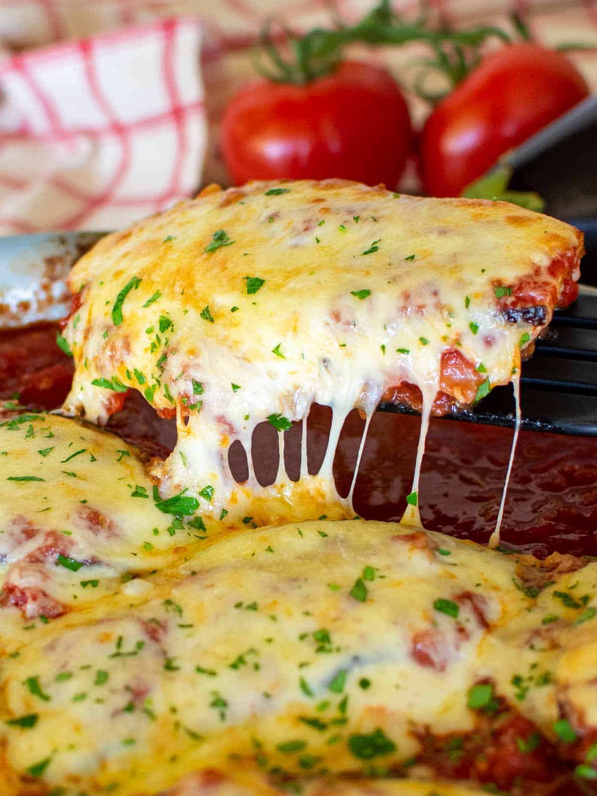 cheese covered Chicken Sorrentino being lifted out of baking dish.