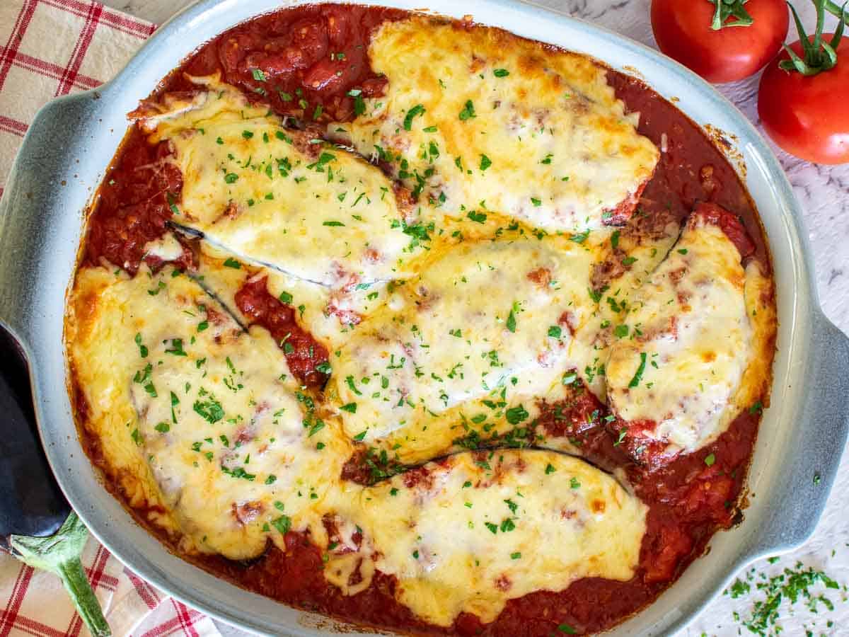 cheesy chicken cutlets in baking dish surrounded by tomato sauce viewed from above.