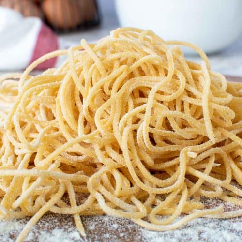 pile of yellow homemade spaghetti on wooden board.