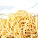 image with text. text reads 'make your own tonnarelli pasta. image is pile of yellow homemade spaghetti on wooden board.