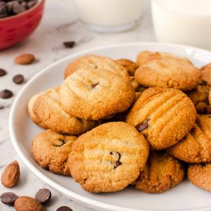 white plate with cookies on and choc chips and almonds scattered nearby.