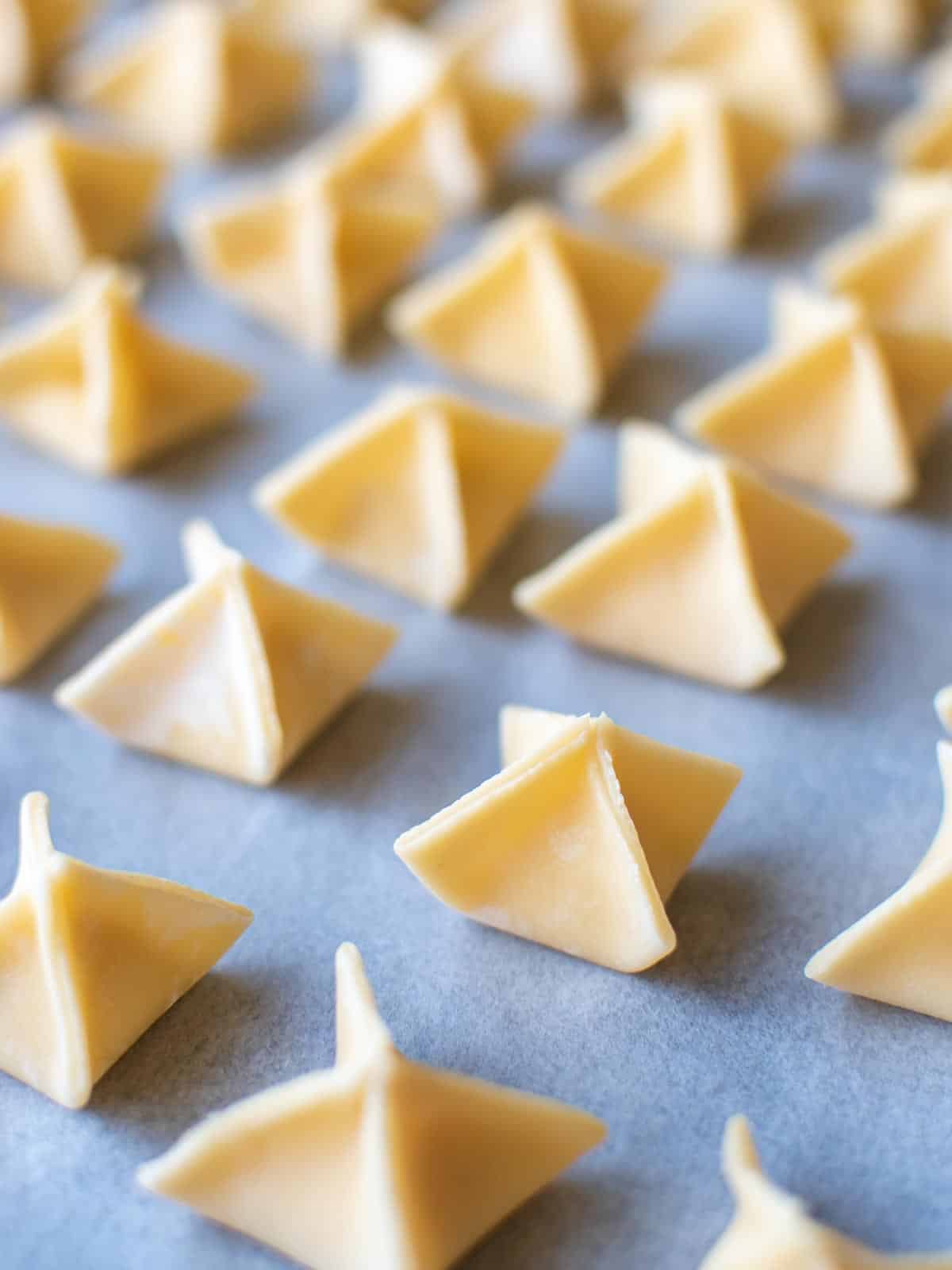 pyramid shaped filled pasta on white baking paper.