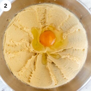 An egg cracked into a bowl of creamy batter.