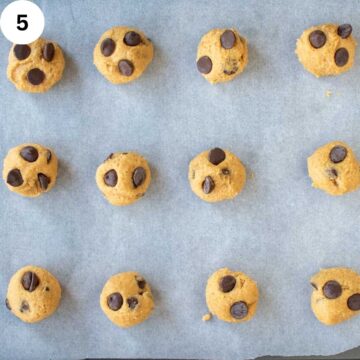 Cookie dough balls with chocolate chips on a baking sheet.